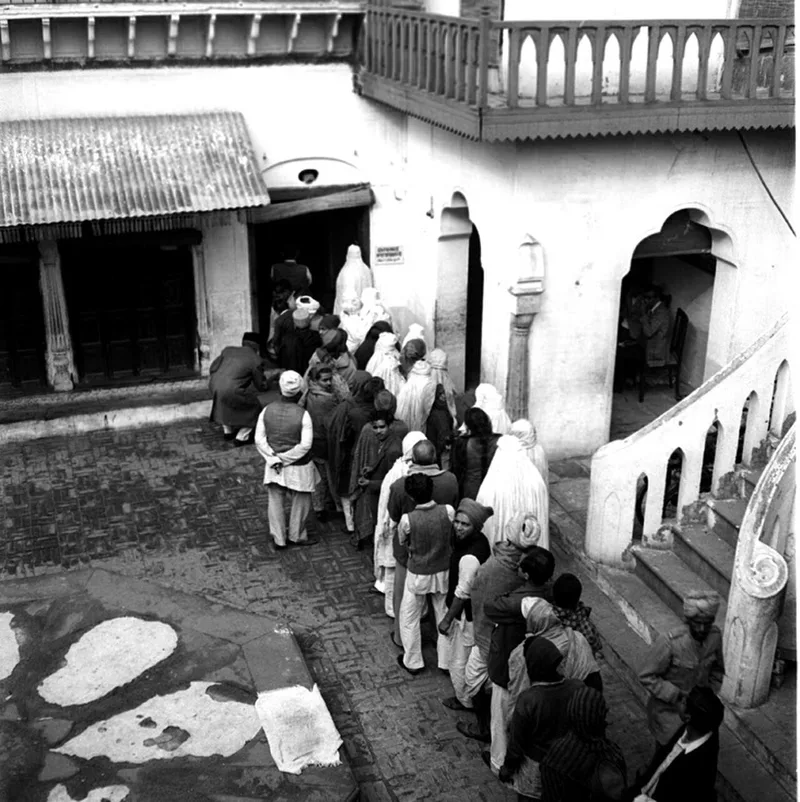 A queue of voters, including women observing purdah in white veils, waiting to cast their votes at a polling booth near Jama Masjid, Delhi, in January 1952