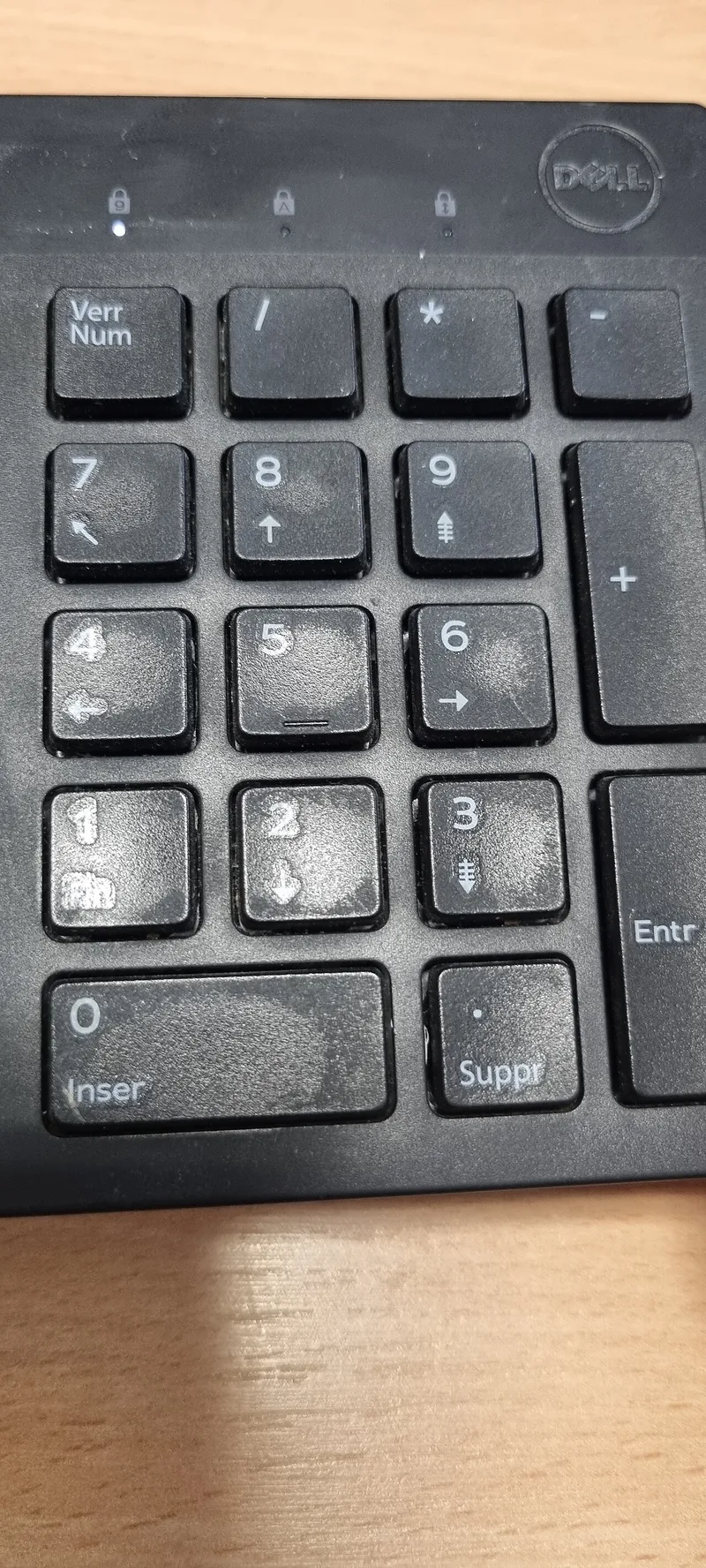 Close-up of a numeric keypad whose most-used number keys are visibly worn and grimed by repeated finger presses, while less-used keys stay clean.