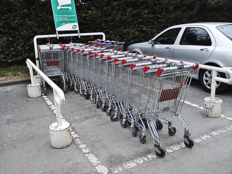 A row of empty shopping trolleys parked outside a supermarket