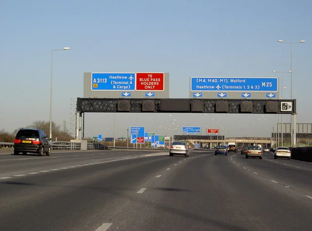 Overhead gantry signs on the M25 motorway near Heathrow, set in the mixed-case Transport typeface, seen from a moving car.