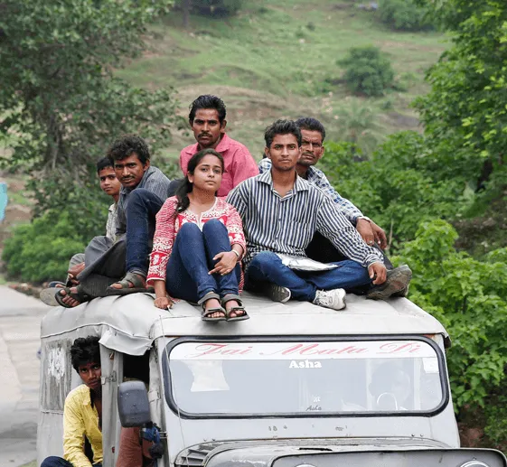 Fellows sitting on the roof of a jeep in a rural landscape