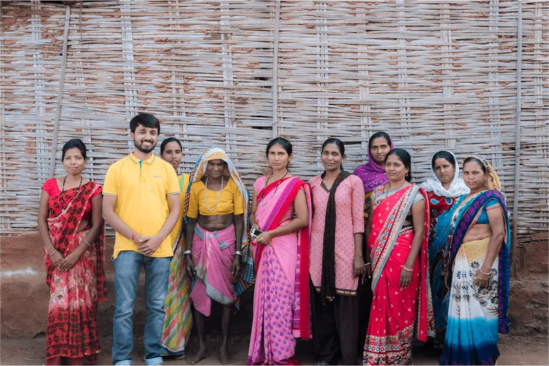 Fellows and community members standing together outside a woven bamboo wall