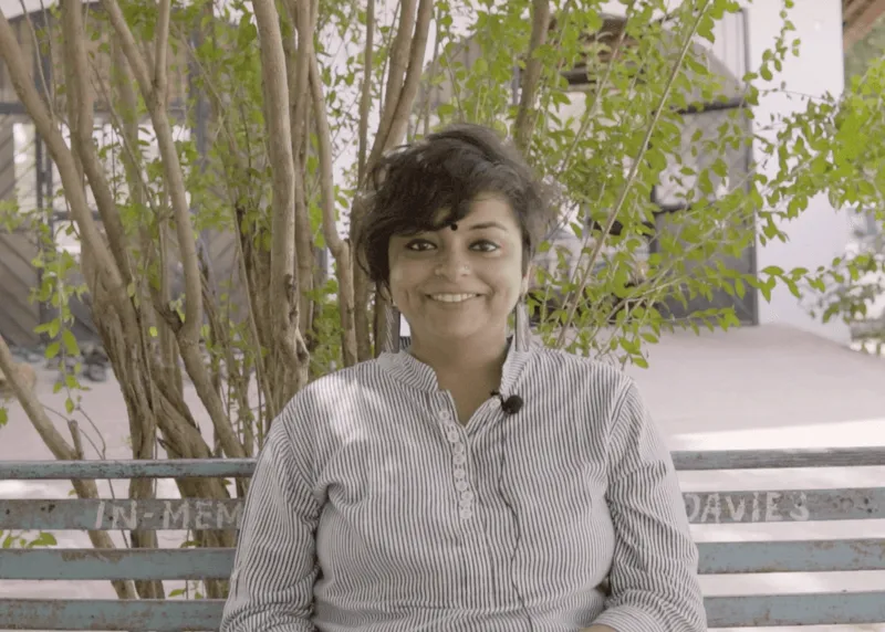 Fellow interview portrait: a short-haired person seated beside trees